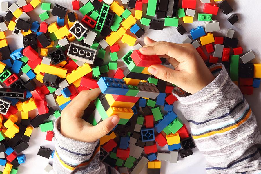 A child's hands playing in a big pile of colourful lego blocks